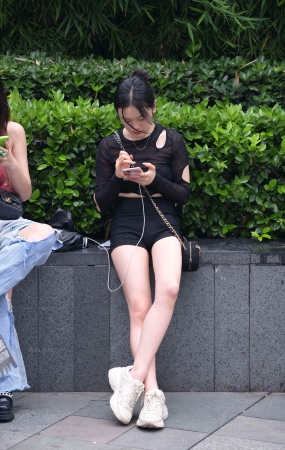 抓拍坐在花坛边的美腿女孩